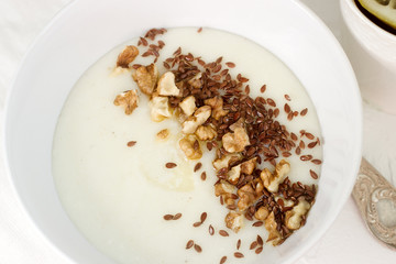 Traditional semolina porridge with butter, nuts and flax seed. A useful breakfast of porridge and tea. Rustic style.