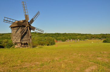 Wind mill is made of wood standing on a green lawn