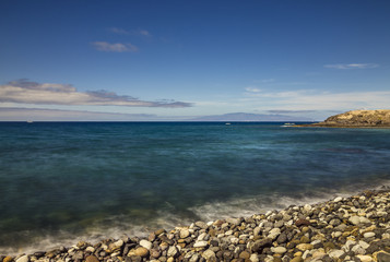 Stony beach in Los Cristianos with La Gomera island on the horizon