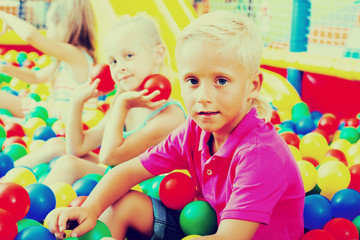 Fototapeta na wymiar Boy sitting and playing with multicolored plastic balls