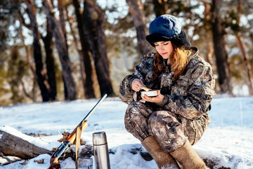 Female hunter preparing food with a portable gas burner in a winter forest. Bushcraft, hunting and people concept