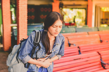 Travel Concept. Beautiful girl is having severe stomach pain while traveling. Asian women are not...