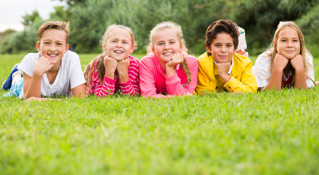 Portrait of five kids who are walking and posing lying