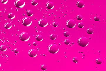 Round water droplets background with a pattern of pixels in a hot pink colour.