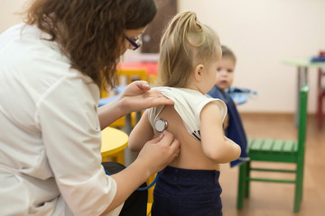 Female doctor examining a child patient in a kindergaten
