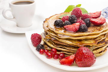 Delicious pancakes with berries and maple syrup on a white background