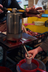 Freshly pressed pomegranate juice being poured into a paper cup