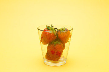 Strawberries in a glass on yellow bakcground 