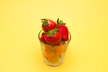 Strawberries in a glass on yellow bakcground 