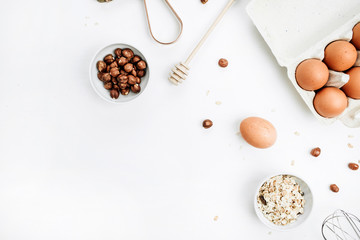 Eggs, hazelnut and cereals on white background. Flat lay, top view.