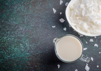 Coconut milk with coconut chips on dark background