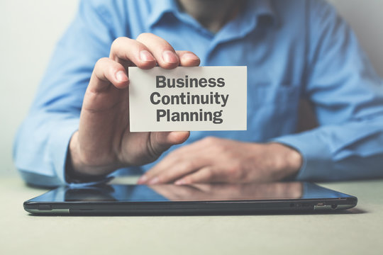 Businessman showing text Business Continuity Planning on business card.