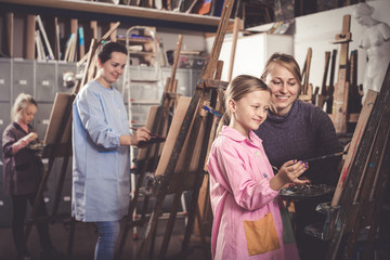 Fototapeta na wymiar Female teacher helping girl during painting class