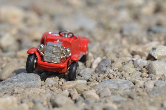 Red model oldtimer toy car driving off road