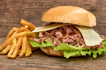 Barbeque Pulled pork Sandwich with green salad,caramelized onion,cheese,Sauce and Fries on wooden background,Fast food