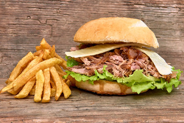 Barbeque Pulled pork Sandwich with green salad,caramelized onion,cheese,Sauce and Fries on wooden background,Fast food