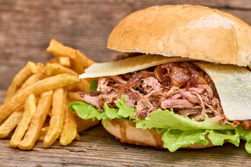 Barbeque Pulled pork Sandwich with green salad,caramelized onion,cheese,Sauce and Fries on wooden background,Fast food