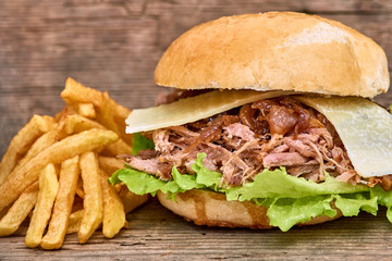 Barbeque Pulled pork Sandwich with green salad,caramelized onion,cheese,Sauce and Fries on wooden background,Fast food