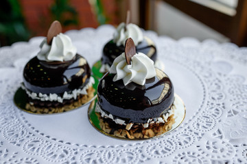Three little brown cakes with white cream and slice of chocolate on top of them