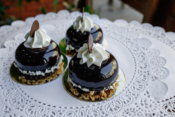 Three little brown cakes with white cream and slice of chocolate on top of them