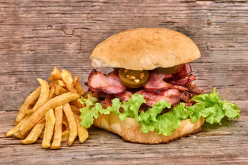 Barbeque Pulled beff Sandwich with green salad,crisp bacon,hot pepper jalapeno,BBQ Sauce and Fries on wooden background,Fast food