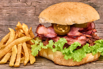 Barbeque Pulled beff Sandwich with green salad,crisp bacon,hot pepper jalapeno,BBQ Sauce and Fries on wooden background,Fast food