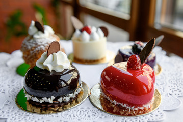 Cakes covered with glance glaze stand on white tablecloth