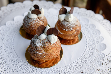 Three little baked cakes decorated with soft white cream and slices of chocolate