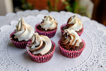 Tasty cupcakes in pink paper and white caramel cream on top