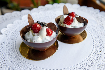 Two chocolate bowls with white cream and berries inside