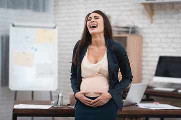 Young pregnant girl is experiencing labor in office. Pregnant in office.