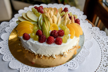Tasty creamy cake decorated with slices of fruits, berries and green grape