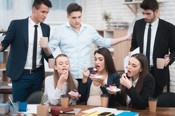 Three young girls eat delicious cake and do not share with men in suits.