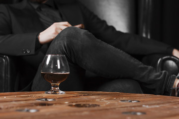 a glass for cognac on a wooden table on the background of a leather chair.