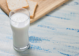 Kefir, yogurt in a glass on a background of slices of white bread on a wooden background.