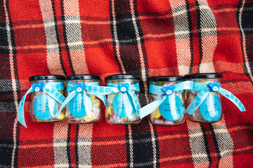 five small jars with cute blue ribbons standing on red blanket