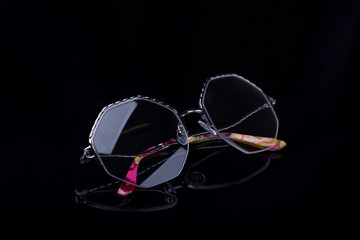 Elegant glasses on a black background with a mirror image