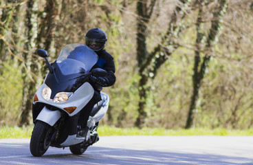 man riding scooter on forest road