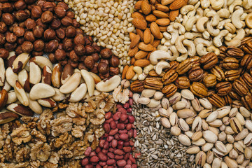 Obraz premium Nuts mix in a canvas bag in table. Ten kinds of nuts: pecan, brazil, cedar, sunflower, hazelnut, almond, peanut walnut pistachio cashew
