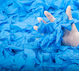 Hand in new white latex medical glove on background of a lot blue rubber gloves