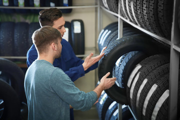 Service center consultant helping customer to choose tire in store - obrazy, fototapety, plakaty