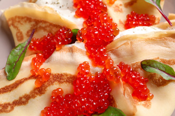 Thin pancakes with red caviar, closeup