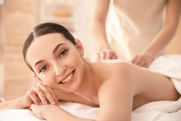 Fototapeta na wymiar Beautiful young woman having massage with body scrub in spa salon