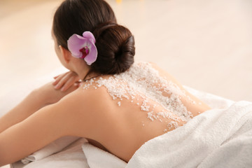 Obraz na płótnie Canvas Beautiful young woman with body scrub on her back in spa salon