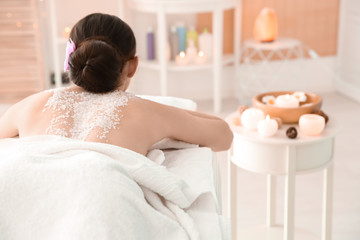 Obraz na płótnie Canvas Beautiful young woman with body scrub on her back in spa salon