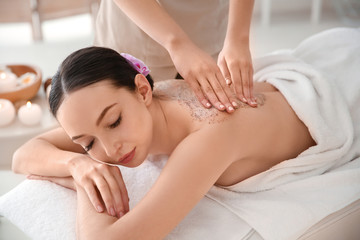 Obraz na płótnie Canvas Beautiful young woman having massage with body scrub in spa salon