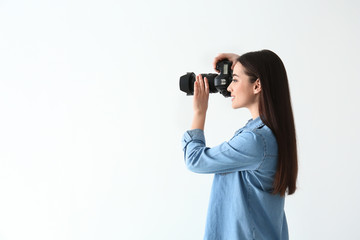 Female photographer with camera on light background