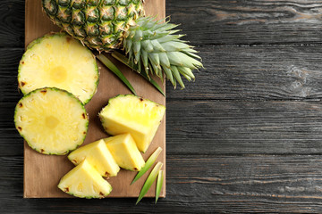 Wooden board with fresh sliced pineapple on table, top view