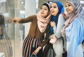 Islamic women friends shopping together at store - obrazy, fototapety, plakaty