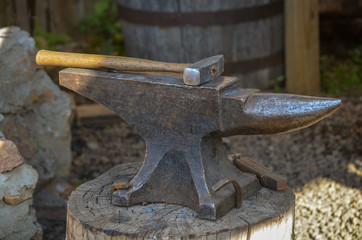 Blacksmith anvil and hammer on stump
